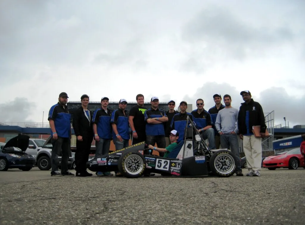 guys in blue shirts standing around car 52